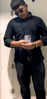 Stylish individual taking a mirror selfie in black attire.