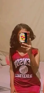 Mirror selfie with trendy red jersey and heart emoji phone cover.