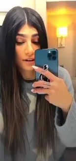 Lady taking a stylish mirror selfie with smartphone.