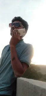 Man with phone against scenic light blue sky.