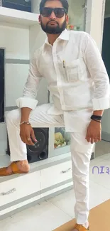 Man in stylish white outfit and sunglasses indoors.