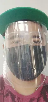 Person in face shield and cap for mobile wallpaper.