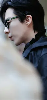 Profile of a stylish person in sunglasses, wearing dark clothes.