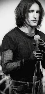 Monochrome portrait of a singer holding a microphone in stylish attire.