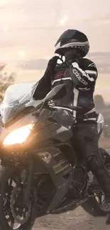 Motorcycle rider in black gear at sunset on open road.