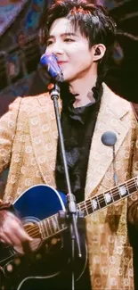 Musician in brown jacket playing guitar on stage with vibrant lights.