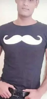 Man in black mustache T-shirt posing confidently.