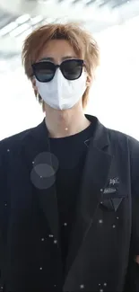 Stylish individual in black blazer and sunglasses with a mask.