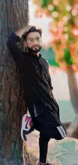 Fashionable individual posing with a tree in nature.