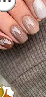 Neutral toned nail art on cozy sweater background.