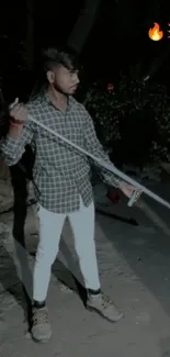 Stylish person holding a rod at night.