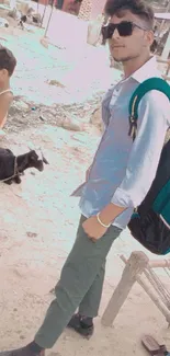 Man in sunglasses with village backdrop and goat.