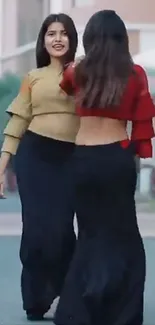 Two fashionable women posing outdoors in stylish outfits.