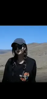 Woman in stylish outfit standing in sunny outdoor landscape.