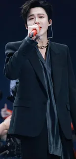 Performer in a sleek black suit holding a microphone.