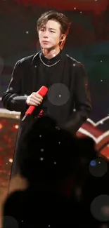 Performer with red microphone on stage in dim lighting.