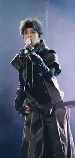 Performer in black outfit singing on a dark blue stage.