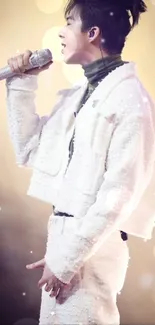 Stylish performer in white outfit singing on stage.