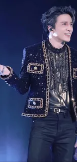 Performer in a sparkling black jacket on stage.