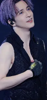 Performer in black sequined vest on stage, smiling passionately.