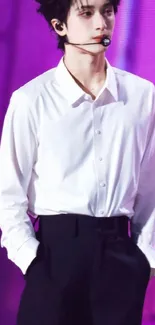 Stylish performer in a white shirt on stage with a purple background.