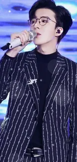 Sleek performer wearing a striped suit singing on stage.