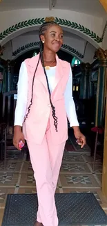 Woman in pink suit standing in an arched entryway with patterned tile floor.