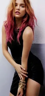 Woman in black dress with pink hair in stylish pose against a minimalist background.