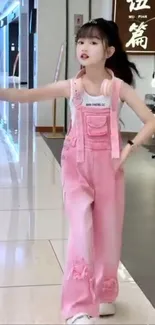 Chic girl in pink overalls in a stylish indoor setting.