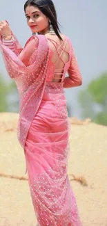 Woman in a pink saree in a rural setting.