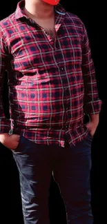 Man in red plaid shirt on a black background.