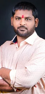 Confident man posing in light pink shirt on dark background.