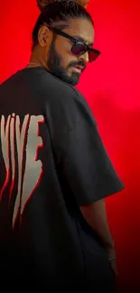 Person in a black T-shirt with red backdrop.