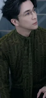 Stylish man in dark green shirt sitting on stairs.