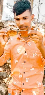 Young man in orange shirt with stylish sunglasses outdoors.