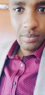 Close-up portrait of a man in a maroon polka-dot shirt and light brown blazer.