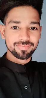 Portrait of young man in black shirt with blue-gray background.