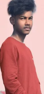 Stylish person against a soft pink background, wearing a red shirt.