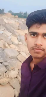 Stylish man in purple shirt with stone background.