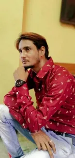 Man in red shirt posing thoughtfully indoors.