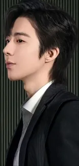 Profile of a person in a black suit with striped background.