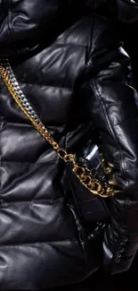 Black quilted leather jacket with gold chain detail.