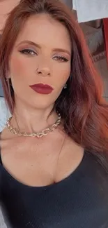 Portrait of a stylish woman with red hair and a black outfit.