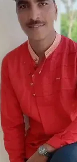 Man in a red shirt posing stylishly against a light background.