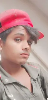 Young person in red cap and gray shirt posing stylishly.