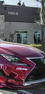 Red luxury car parked outside modern building.