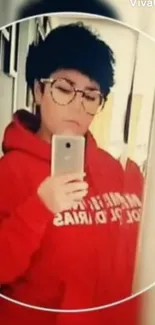 Person in red hoodie taking a mirror selfie.