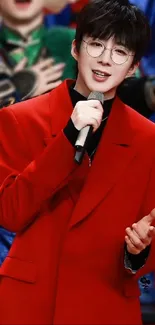 Performer in red coat holding microphone, smiling.