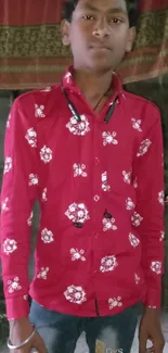 Young man wearing a red shirt stands confidently indoors.