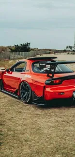 Sleek red sports car on a coastal road, perfect for mobile wallpaper.